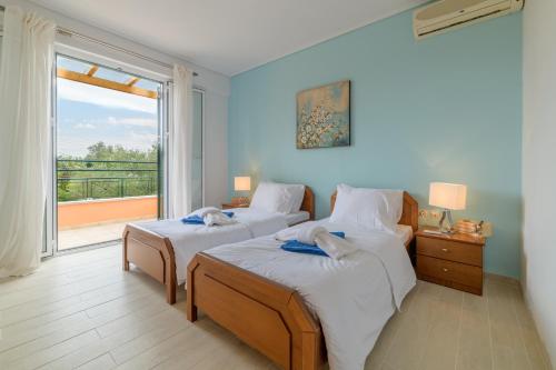 a bedroom with two beds and a large window at Alexios Villa in Ágios Ioánnis