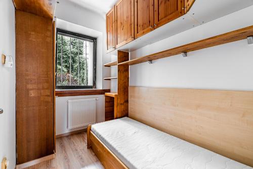 um pequeno quarto com uma cama e uma janela em Apartman Xaveriova em Praga