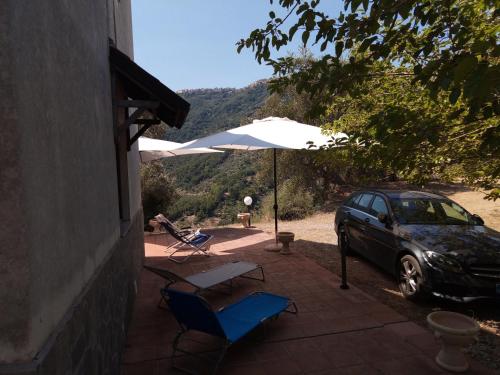 eine Terrasse mit einem Auto, einem Sonnenschirm und Stühlen in der Unterkunft L'Antica Quercia B&B in CastellʼUmberto