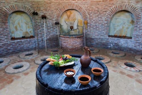 a wooden table with a bowl of food and a vase at Tskaltubo Epic Hotel & Spa in Tskaltubo