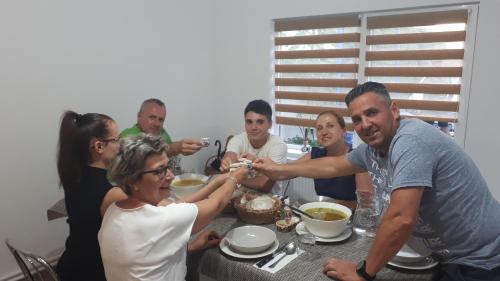 a group of people sitting around a table eating food at Lörincz Vendégház in Corund
