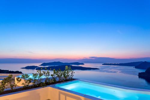 a villa with a swimming pool at sunset at Alti Santorini Suites - Caldera View in Megalochori