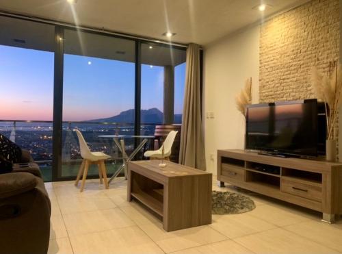 a living room with a flat screen tv and a large window at On the GBay Villa in Gordonʼs Bay