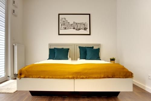 - une chambre dotée d'un grand lit avec des oreillers jaunes et bleus dans l'établissement Essence Apartments Amber, à Poznań