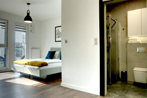 a bedroom with a bed and a bathroom at Essence Apartments Amber in Poznań