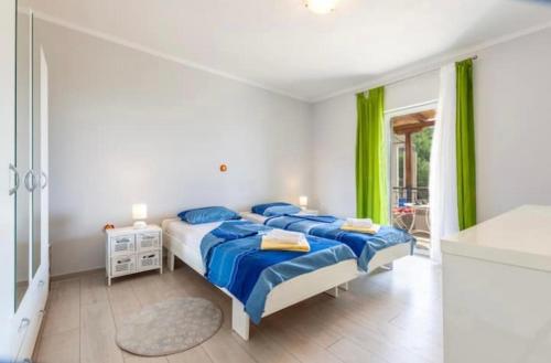 een slaapkamer met een bed met blauwe lakens en groene gordijnen bij Kuca za odmor Veronika in Jesenice