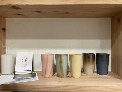a row of different colored vases sitting on a shelf at ゲストハウス WAKURIAN-Iwatacho in Kaigandōri