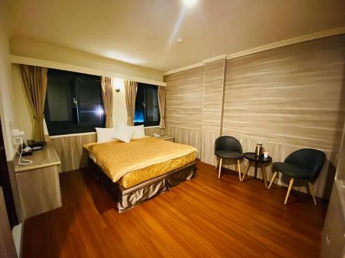 a bedroom with a bed and two chairs in it at Yin Shan Hotel in Zhongzheng