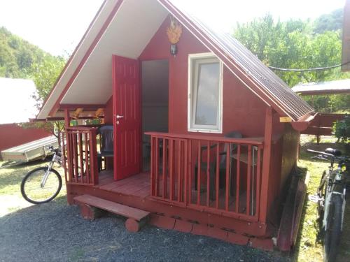 ein rotes Haus mit einem Fenster und einem Fahrrad draußen in der Unterkunft La casuta de pe vale in Brănişca