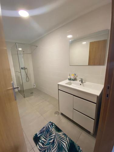 a bathroom with a sink and a shower with a mirror at Casa da Clemencia in Cardeal