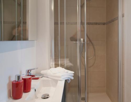 ein Badezimmer mit einem Waschbecken und einer Dusche mit roten Tassen in der Unterkunft Wellintown Guest House in Waterloo