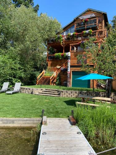 a log cabin with a wooden walkway next to a lake at THE INN Bigfork Bay in Bigfork
