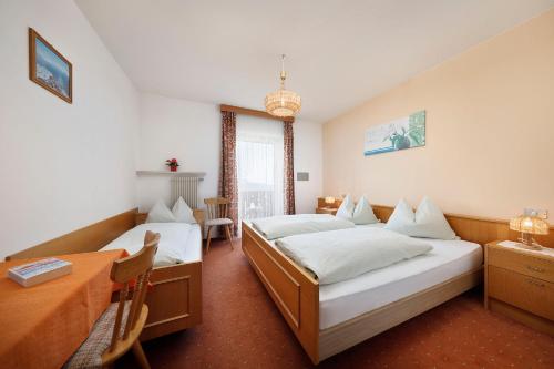 a bedroom with two beds and a desk and a table at Gasthof Mesnerwirt in Auna di Sopra