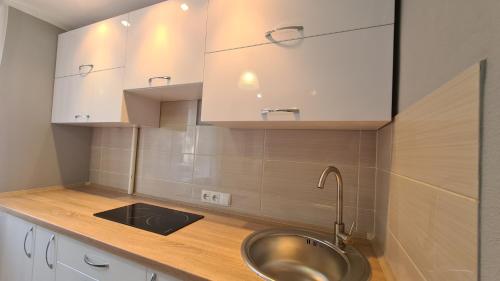 cocina con fregadero y armarios blancos en Apartaments on vulytsia Heroiv Ato 32 (97th Kvartal), en Krivoy Rog