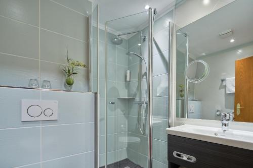 a bathroom with a glass shower and a sink at Hotel St. Georg Garni in Celle
