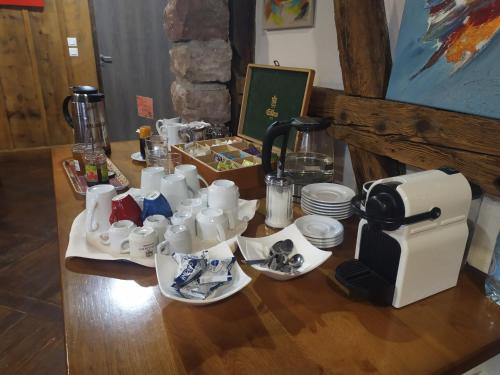 a table with cups and a coffee maker on it at Hotel Relais d'ISSENHEIM Table d'hôtes in Issenheim