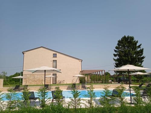 einem Pool mit Stühlen und Sonnenschirmen vor einem Gebäude in der Unterkunft agriturismo Casa Pezzo in Castelnuovo del Garda