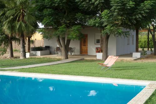 una casa con piscina e una sedia accanto di Preciosa y confortable casa de campo con piscina y chimenea a Carmona