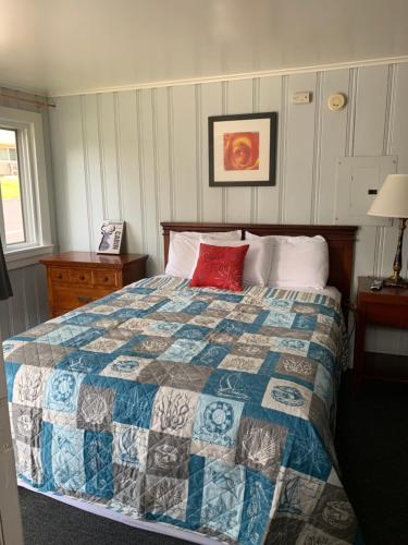 a bedroom with a bed with a red pillow on it at Northeaster Motel in Kittery