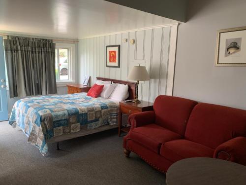 Habitación de hotel con cama y sofá rojo en Northeaster Motel, en Kittery