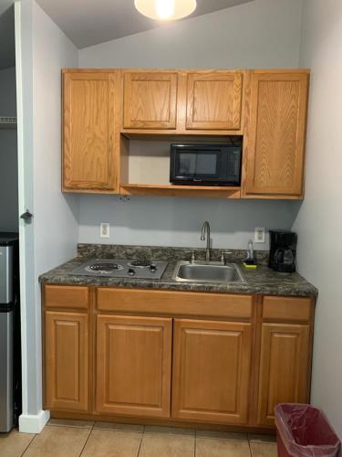 a kitchen with wooden cabinets and a sink and a microwave at Northeaster Motel in Kittery