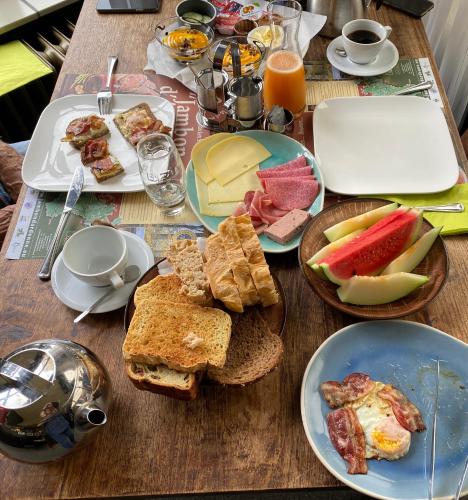 een houten tafel met borden ontbijtproducten erop bij De Post B&B Restaurant in Klimmen