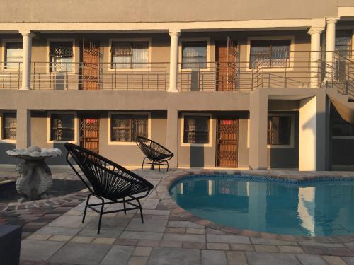 a building with two chairs next to a swimming pool at Asante’s Guest House in Calcutta