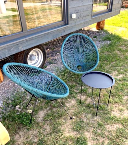 two blue chairs and a table in front of a bus at Pixel - Tiny Campus in Tîrgu Secuiesc