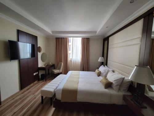 Cette chambre comprend un grand lit et une télévision. dans l'établissement Goha Addis Hotel, à Addis-Abeba