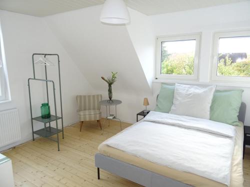 a white bedroom with a bed and two windows at FeWo am Deister in Bad Münder am Deister