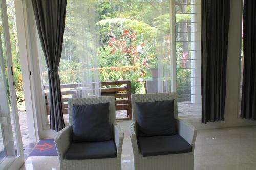 two chairs sitting in front of a large window at The Forest Villa in Bogor