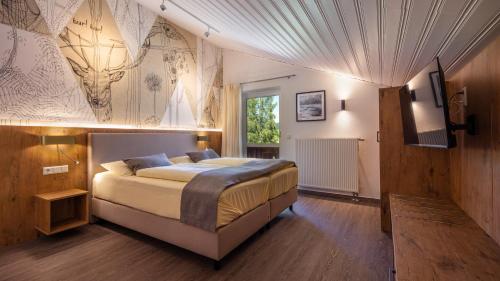 ein Schlafzimmer mit einem Bett und einer Wand mit einem Hirsch-Wandbild in der Unterkunft Aparthotel Chiemgaufuchs in Inzell