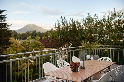 d'un balcon avec une table et des chaises en bois et une montagne. dans l'établissement HOMEBOUND APARTMENTS Salzburg City I - contactless check-in, à Salzbourg