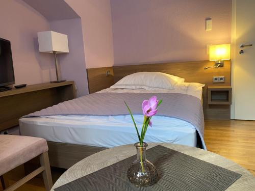 a vase with a flower on a table in a bedroom at Pension Jeske Heidelberg in Heidelberg