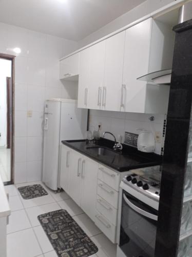 a kitchen with white cabinets and a sink and a refrigerator at Apto Carioca Shopping in Campos dos Goytacazes
