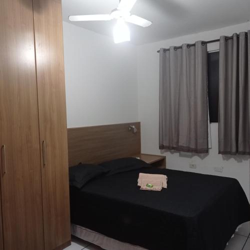 a bedroom with a black bed and a ceiling fan at Apto Carioca Shopping in Campos dos Goytacazes