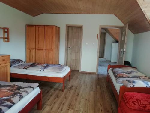 two beds in a room with wooden floors at Agro Zula in Hrabušice