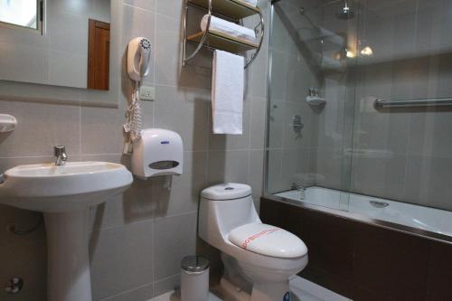 a bathroom with a toilet and a sink and a phone at Hotel Puerto Banana in El Guabo