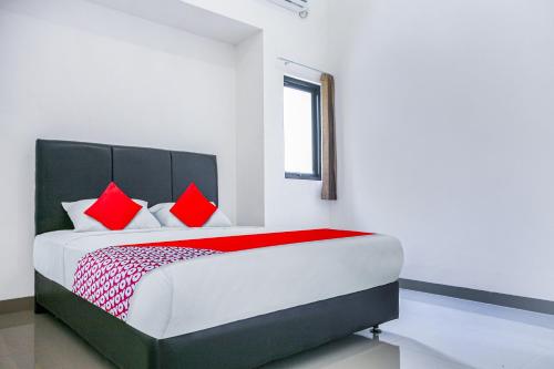 1 dormitorio con 1 cama grande con almohadas rojas en OYO 3438 Pasir Padi Inn Syariah, en Kebinti