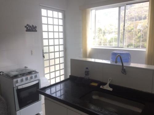 a kitchen with a sink and a stove and windows at Apartamento Turismo 2 quartos em Águas de Lindóia, Natureza!!!! in Águas de Lindoia