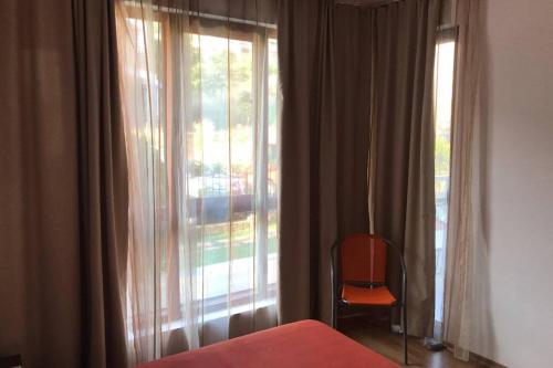 a bedroom with a bed and a window with a chair at Комфортное жильё в 250 метрах от моря ! in Sveti Vlas