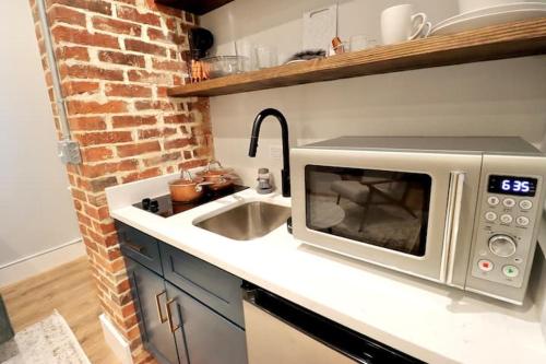 a kitchen counter with a microwave and a sink at The Queen Suite at Prince Street Inn in Alexandria