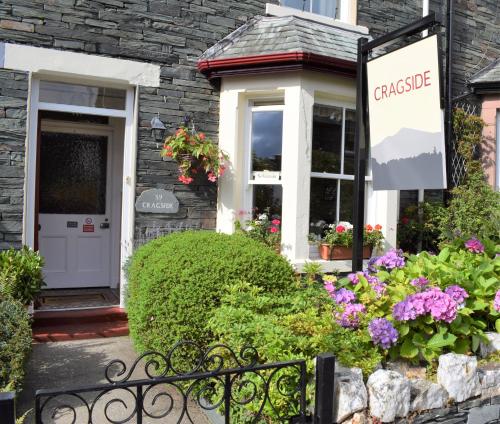 a sign in front of a house with flowers at Cragside Guest House in Keswick