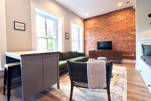 a living room with a green couch and a brick wall at The Franklin Suite at Prince Street Inn in Alexandria