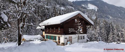 ein Blockhaus mit Schnee darüber in der Unterkunft Alpengasthof Wegscheid in Kelchsau