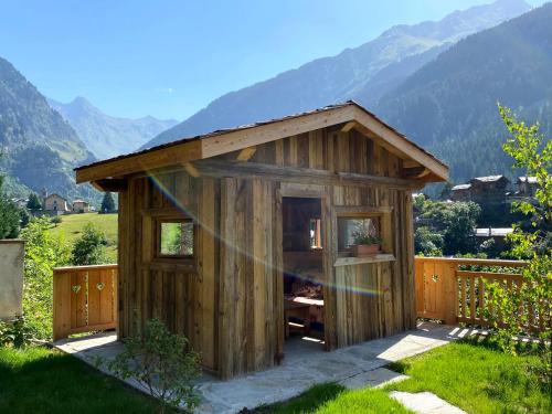 a small wooden shed in a field with mountains at Chalet des Trappeurs Coeur Vanoise 15 persons in Champagny-en-Vanoise