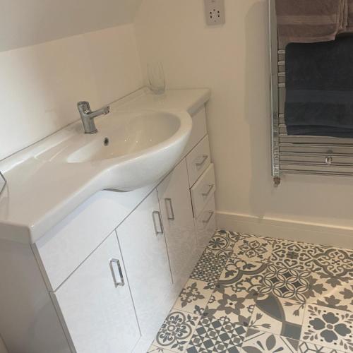 a white bathroom with a sink and a tile floor at Attic views in Caol