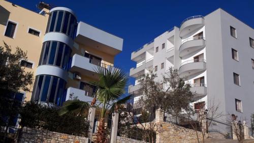 "Adriatik Hills" Apartments COMPLEX في دوريس: مبنى ذو اعمدة زرقاء بجانب مبنى
