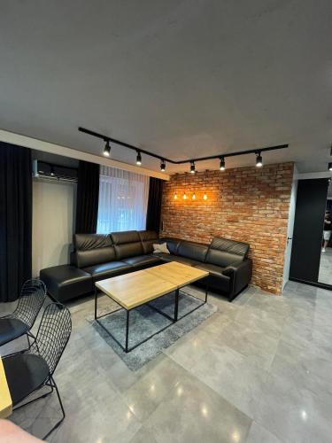 a living room with leather furniture and a brick wall at Luksusowy Apartament Solankowa Aleja in Inowrocław
