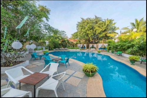 una piscina con tavoli e sedie accanto a un resort di Casa Arya Villa a Sinquerim